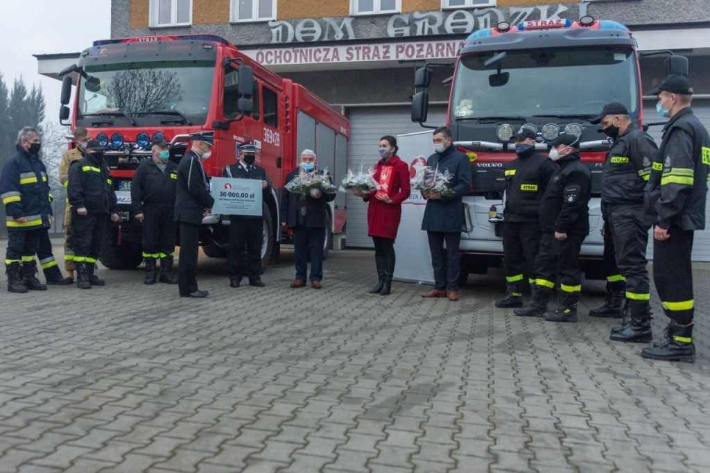 Burmistrz Wojnicza w otoczeniu strażaków przekazujący promesę na zakup sprzętu