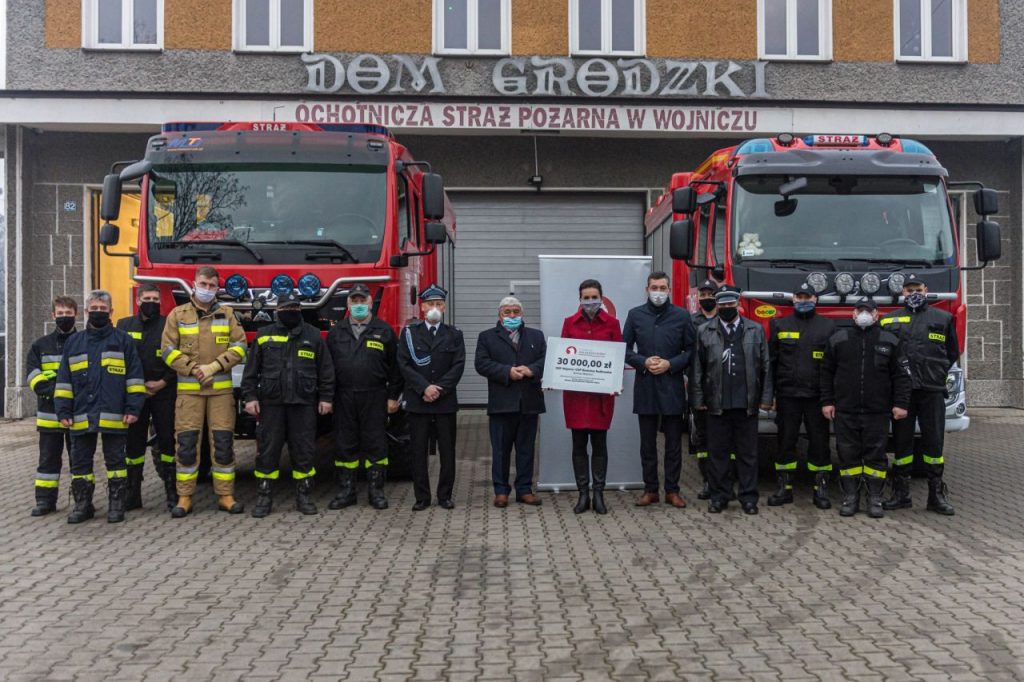 Burmistrz Wojnicza w otoczeniu strażaków przekazujący promesę na zakup sprzętu