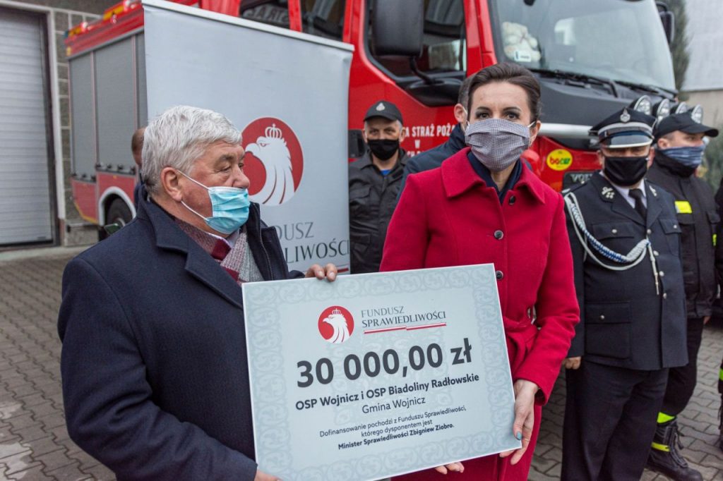 Burmistrz Wojnicza w otoczeniu strażaków przekazujący promesę na zakup sprzętu