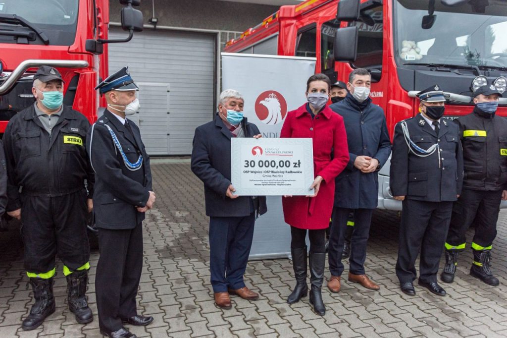 Burmistrz Wojnicza w otoczeniu strażaków przekazujący promesę na zakup sprzętu