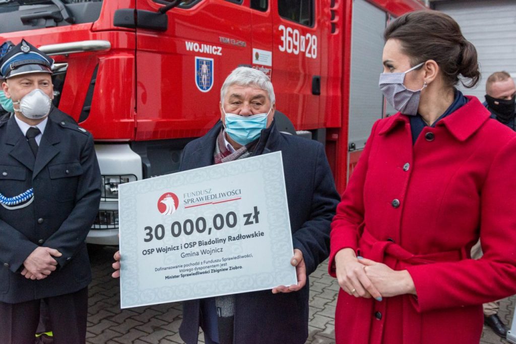 Burmistrz Wojnicza w otoczeniu strażaków przekazujący promesę na zakup sprzętu