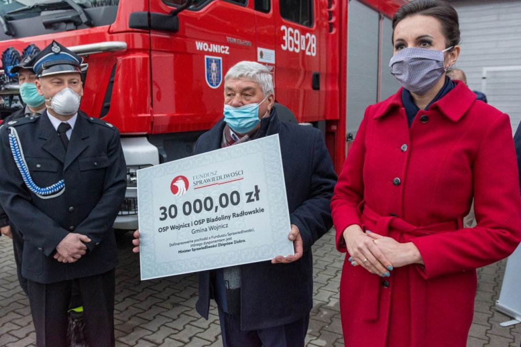 Burmistrz Wojnicza w otoczeniu strażaków przekazujący promesę na zakup sprzętu