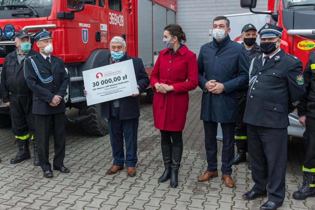 Burmistrz Wojnicza w otoczeniu strażaków przekazujący promesę na zakup sprzętu