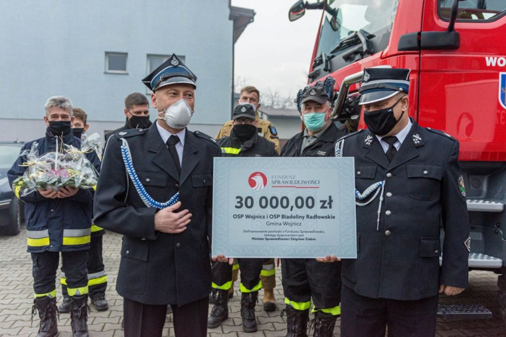 Burmistrz Wojnicza w otoczeniu strażaków przekazujący promesę na zakup sprzętu