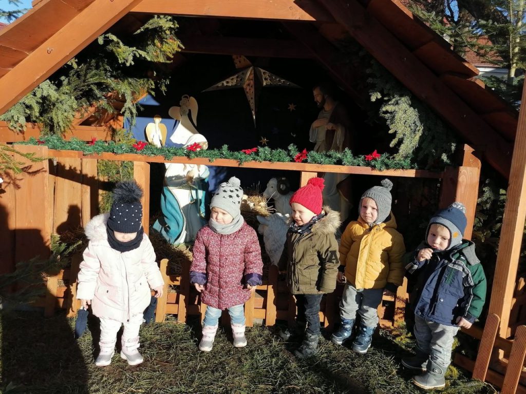 Dzieci przed szopką w świetle słońca