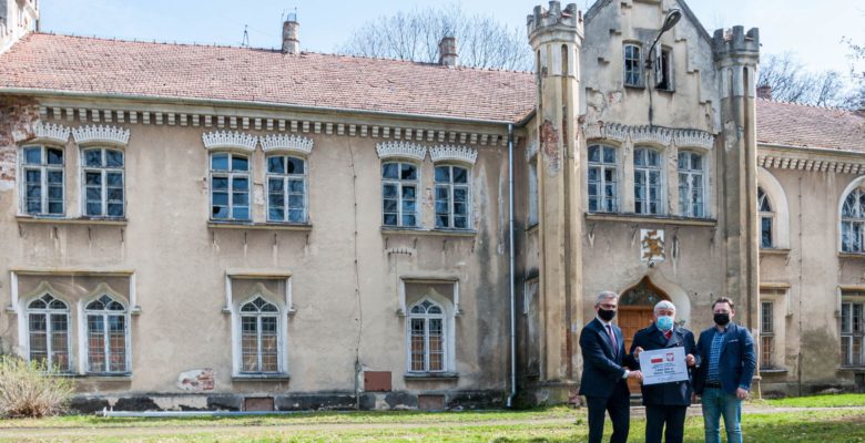 Zdjęcie przekazanie promesy na tle Pałącu Dąbskich w Wojniczu.