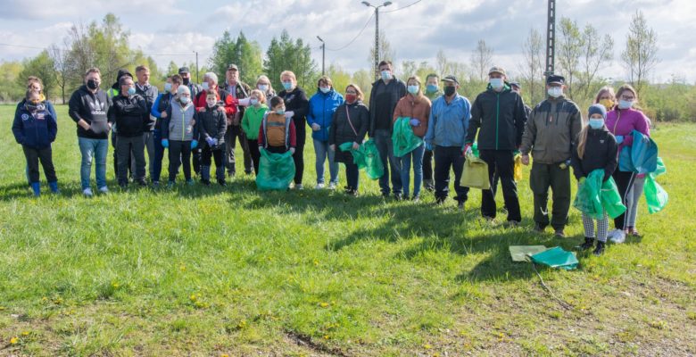 Wiele osób stojących na trawie w rękach trzymających worki na śmieci